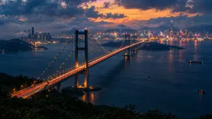 Dlouhý most přes tmavou vodu k zářícímu panoramatu města za soumraku