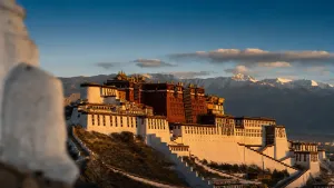 Palác Potala ve Lhase za zlatého světla nad tibetskou náhorní plošinou se zasněženými vrcholky