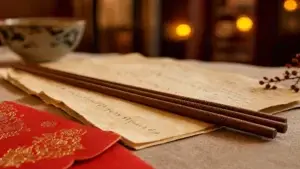 Dřevěné hůlky a hongbao červená obálka na starém papíru, symbol rodinného setkání přes vízum Q