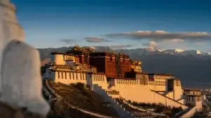 Palác Potala ve Lhase za zlatého světla nad tibetskou náhorní plošinou se zasněženými vrcholky
