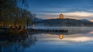 Západní jezero v Hangzhou za modré hodiny s pagodou Leifeng a mlhou nad hladinou