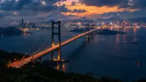 Dlouhý most přes tmavou vodu k zářícímu panoramatu města za soumraku